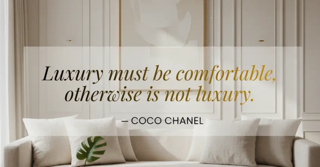 "A luxury interior design showroom featuring a neutral-toned sofa with plush pillows against a decorative wall panel. Overlaid in elegant gold italicized serif font is the Coco Chanel quote: 'Luxury must be comfortable, otherwise it is not luxury.'"
